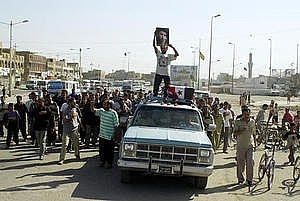 un uomo iracheno alza un poster del Shiita al-Sadar