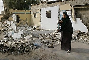 donna palestinese pulisce libera i resti della sua casa dalle macerie