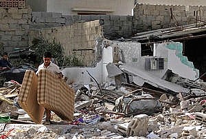 uomo israeliano porta VIA I MATERASSI DALLE MACERIE DELLA SUA CASA