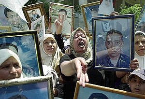 donne palestinesi mostrano le foto dei loro mariti imprigionati